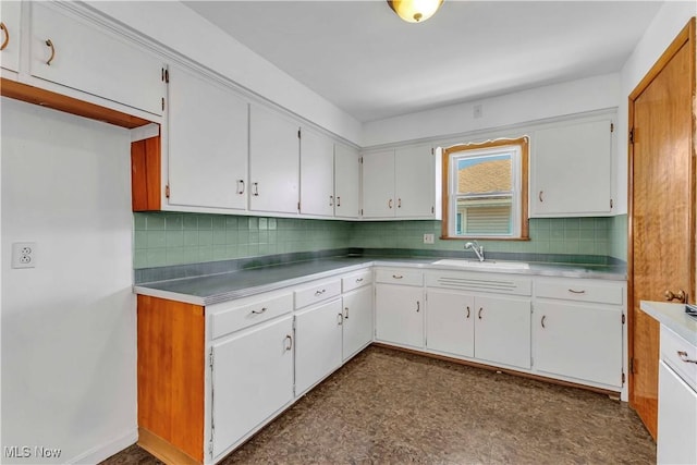 kitchen with white cabinets, dark floors, backsplash, and a sink