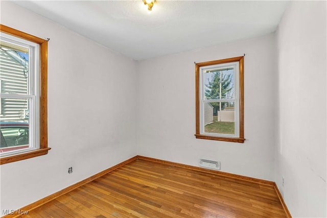 spare room with visible vents, baseboards, and hardwood / wood-style flooring