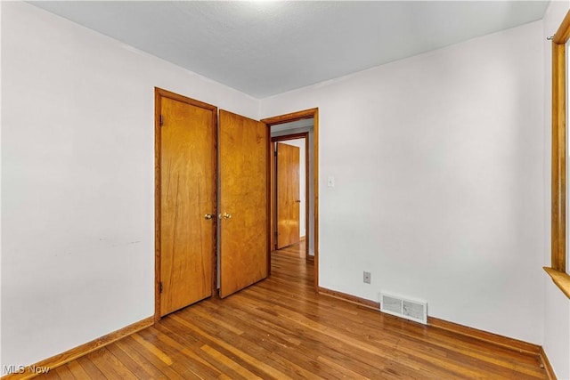 unfurnished bedroom featuring a closet, visible vents, baseboards, and hardwood / wood-style flooring