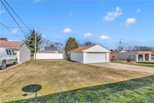 view of yard featuring a detached garage, an outdoor structure, and fence