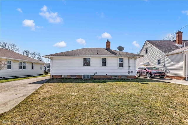 back of house featuring concrete driveway, a yard, central AC unit, and a chimney