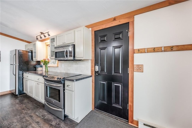 kitchen with baseboards, decorative backsplash, baseboard heating, appliances with stainless steel finishes, and white cabinetry