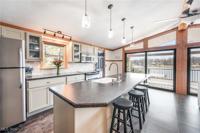 kitchen featuring dark countertops, lofted ceiling, a wealth of natural light, appliances with stainless steel finishes, and a sink