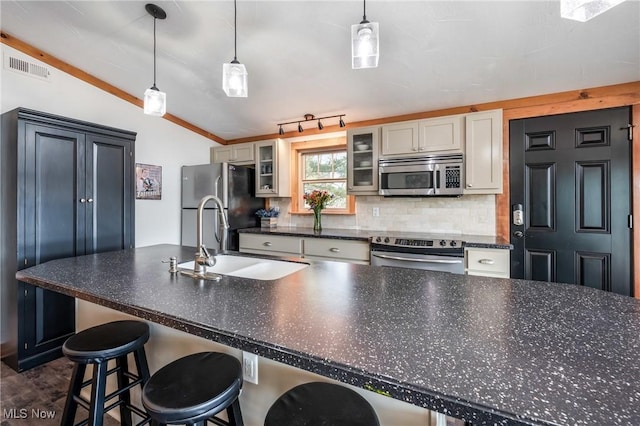 kitchen featuring tasteful backsplash, visible vents, dark countertops, vaulted ceiling, and appliances with stainless steel finishes