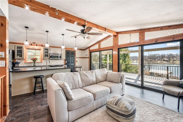 living area with a water view, lofted ceiling with beams, rail lighting, ceiling fan, and dark wood-style flooring