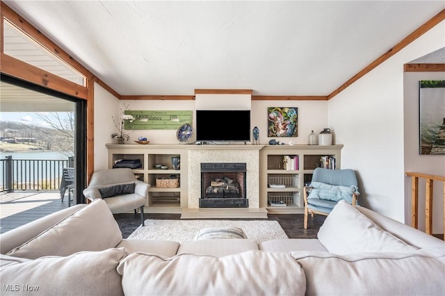 living area with wood finished floors, a fireplace with raised hearth, and ornamental molding