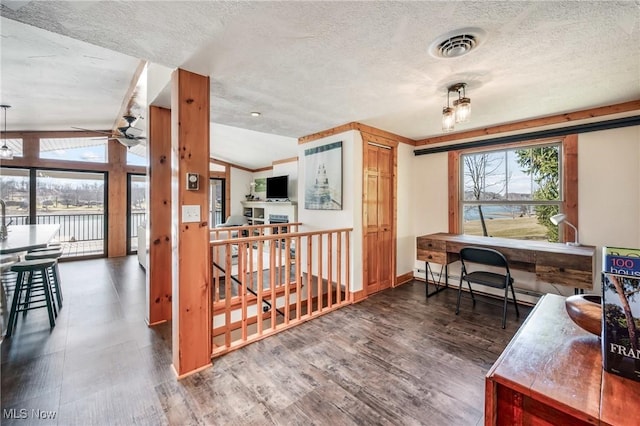 home office with wood finished floors, visible vents, a baseboard radiator, vaulted ceiling, and a textured ceiling