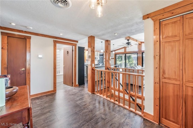 hall with an upstairs landing, visible vents, a textured ceiling, and wood finished floors