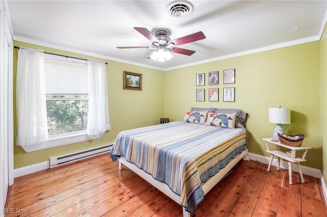 bedroom with visible vents, baseboards, ornamental molding, hardwood / wood-style floors, and a baseboard radiator