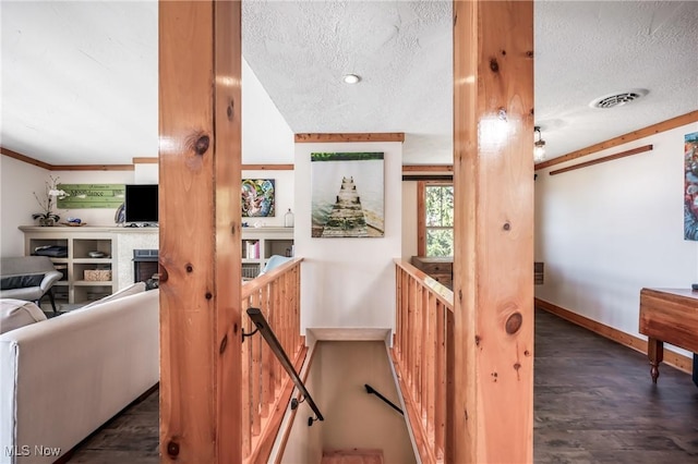 stairs with visible vents, a textured ceiling, baseboards, and wood finished floors