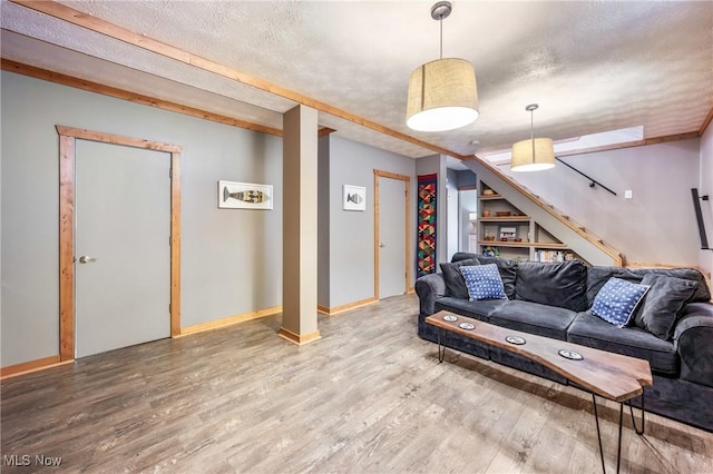 living area featuring stairway, baseboards, a textured ceiling, and wood finished floors