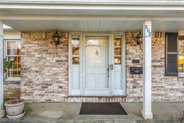 doorway to property featuring brick siding and covered porch