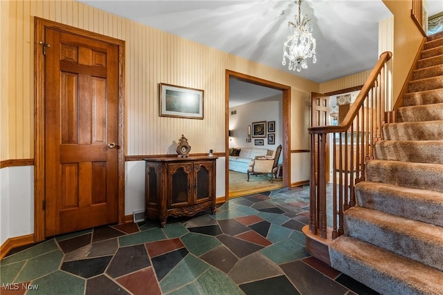 entryway with baseboards, a chandelier, and stairs