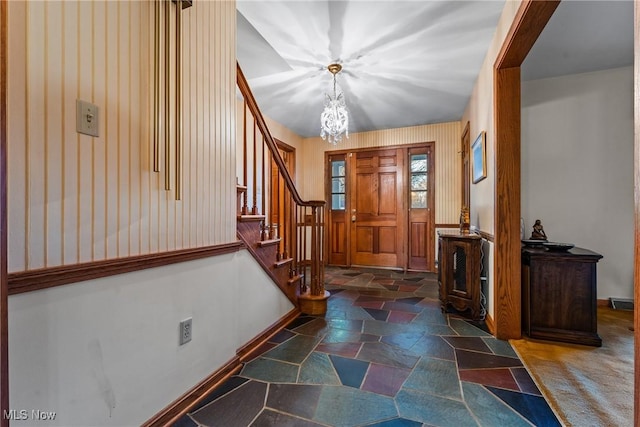 entryway featuring stone tile flooring, stairway, a notable chandelier, and baseboards