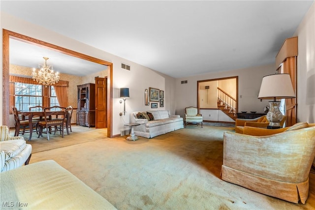 carpeted living room with stairs, a notable chandelier, baseboards, and visible vents