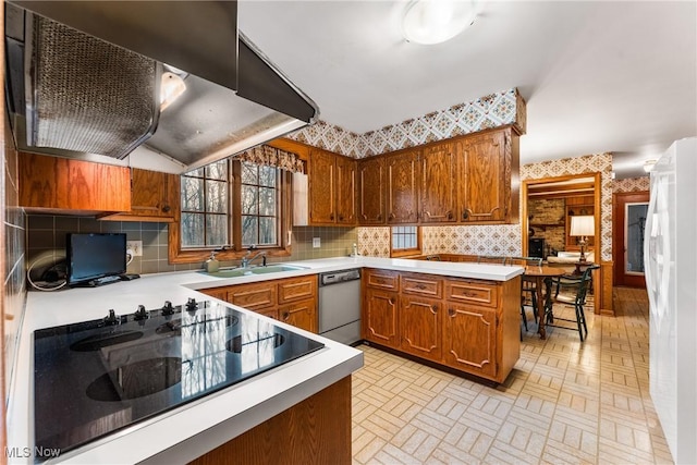 kitchen with dishwashing machine, brown cabinetry, wallpapered walls, a sink, and light countertops