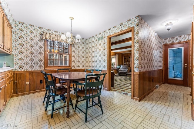 dining room with a wainscoted wall, brick patterned floor, visible vents, and wallpapered walls