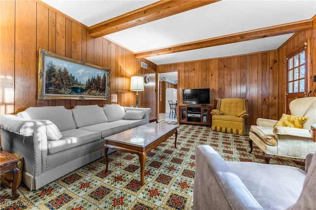 carpeted living room featuring visible vents, beam ceiling, and wood walls