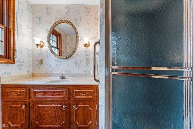 bathroom featuring wallpapered walls, an enclosed shower, and vanity