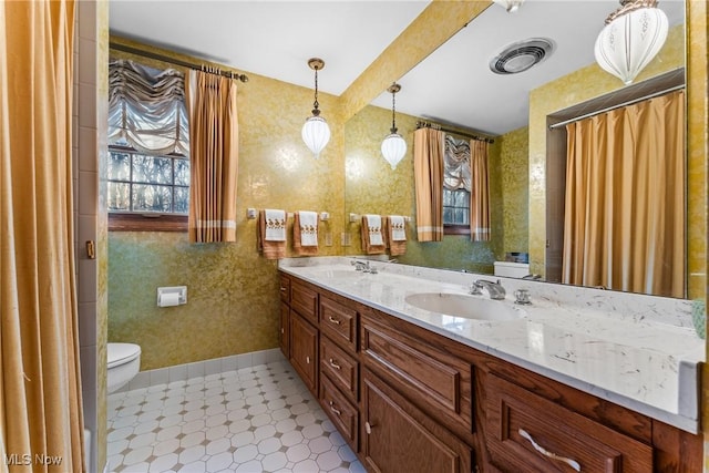 full bathroom with double vanity, baseboards, visible vents, and a sink