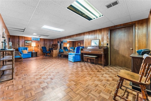 interior space featuring wooden walls, visible vents, and a drop ceiling