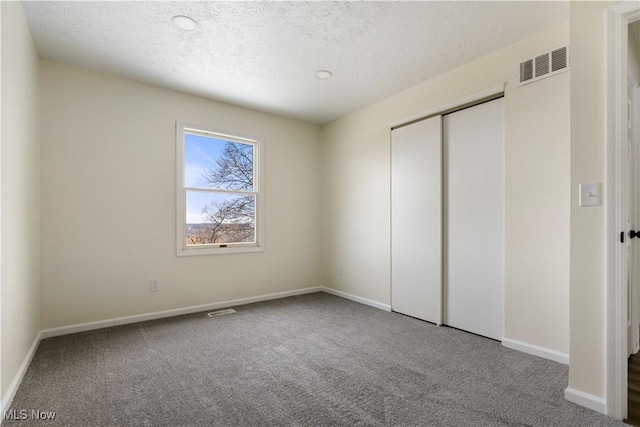 unfurnished bedroom with visible vents, carpet floors, a textured ceiling, and baseboards