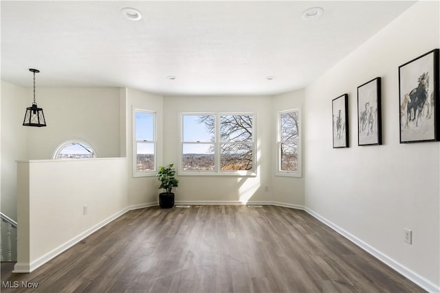 empty room featuring dark wood-type flooring, baseboards, and a wealth of natural light