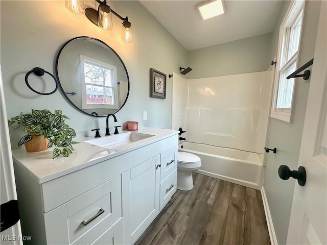 bathroom featuring baseboards, toilet, vanity, wood finished floors, and washtub / shower combination
