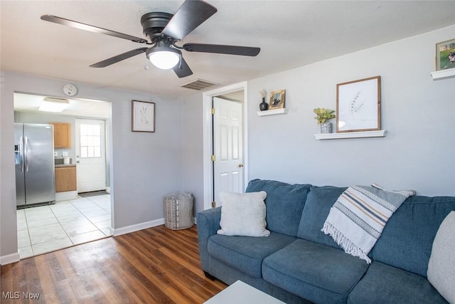 living area featuring visible vents, baseboards, light wood-style floors, and ceiling fan