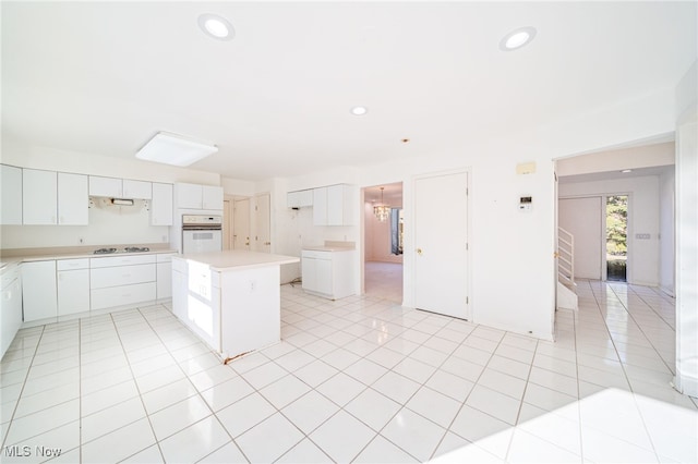 kitchen featuring cooktop, light tile patterned floors, recessed lighting, white oven, and white cabinetry