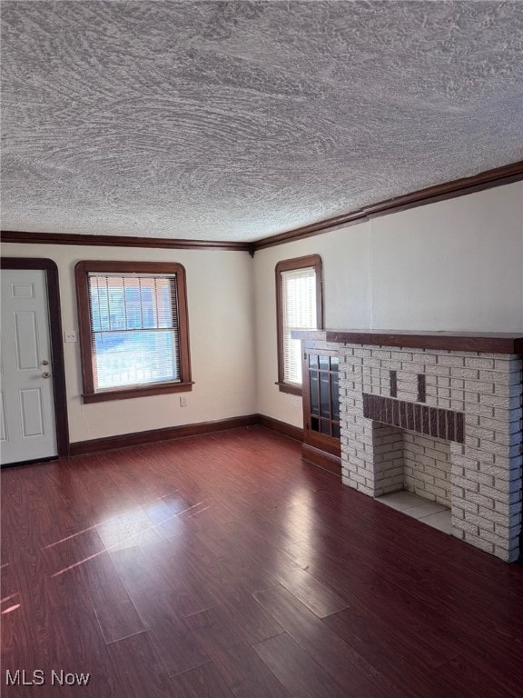 unfurnished living room featuring wood finished floors, crown molding, a fireplace, and baseboards