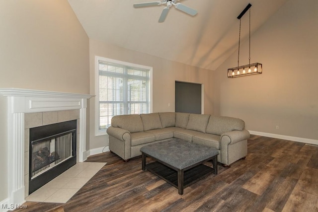 living room with ceiling fan, baseboards, wood finished floors, and a tiled fireplace