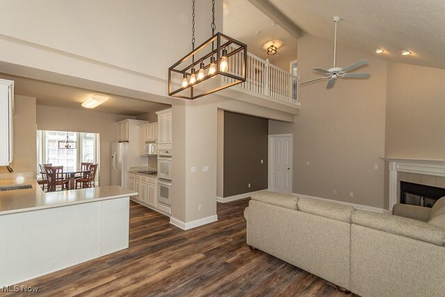 living room with ceiling fan, baseboards, dark wood finished floors, and a tiled fireplace