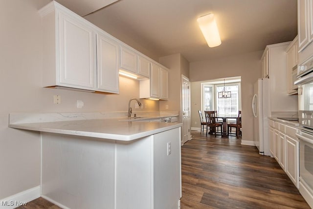 kitchen with a sink, dark wood-style floors, white appliances, white cabinets, and light countertops