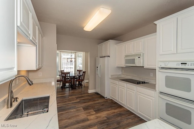 kitchen featuring dark wood finished floors, light stone counters, white appliances, white cabinetry, and a sink