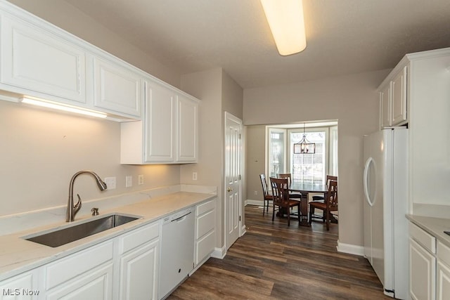 kitchen featuring dark wood-style floors, a notable chandelier, white cabinets, white appliances, and a sink