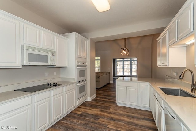 kitchen featuring dark wood-type flooring, a peninsula, white appliances, white cabinetry, and a sink