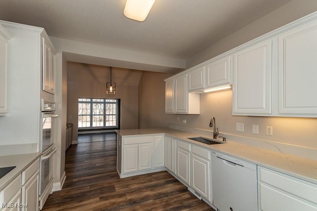 kitchen featuring white cabinetry, a peninsula, a sink, dark wood-type flooring, and dishwasher