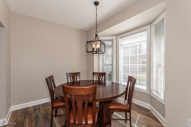 dining room featuring a chandelier, baseboards, and dark wood-style floors