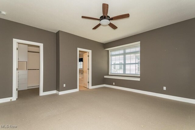 unfurnished bedroom with a spacious closet, baseboards, carpet flooring, a closet, and ensuite bath