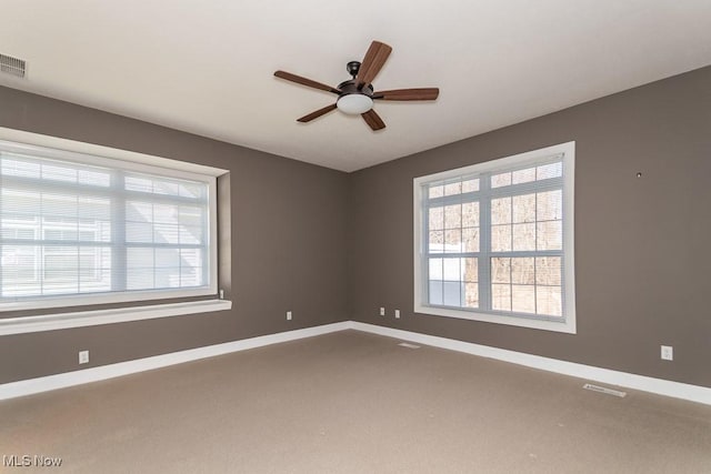 unfurnished room with visible vents, carpet flooring, a ceiling fan, and baseboards