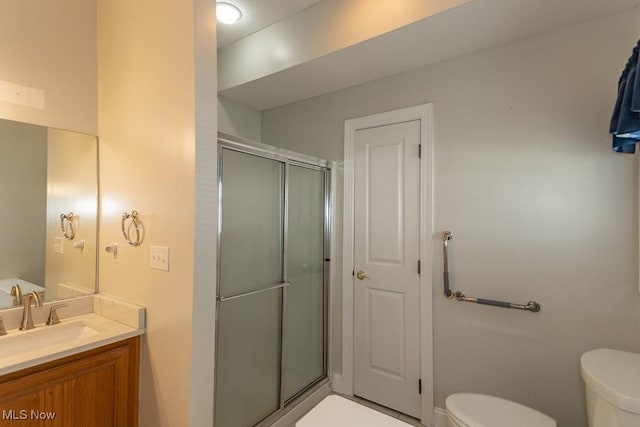 full bathroom featuring vanity, a shower stall, and toilet