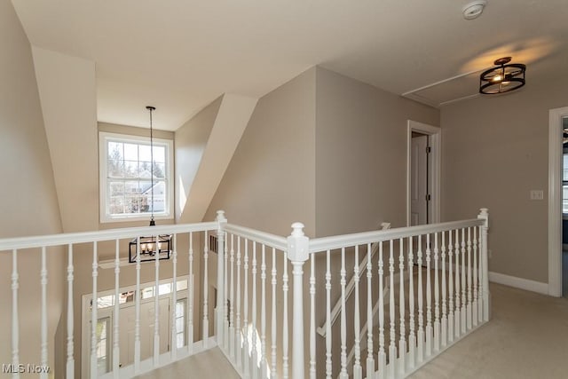 hall with baseboards, carpet, and a chandelier