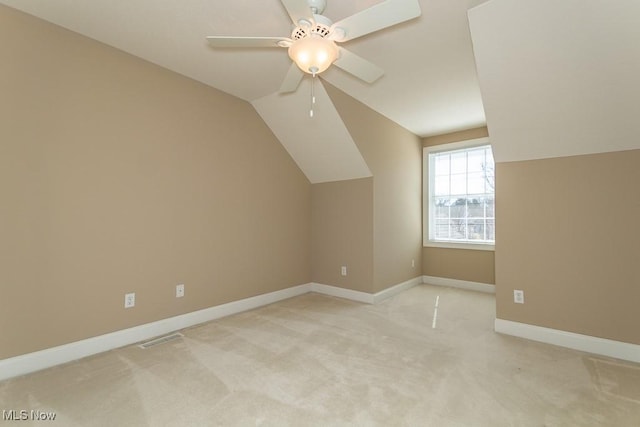 additional living space with a ceiling fan, baseboards, visible vents, vaulted ceiling, and light carpet