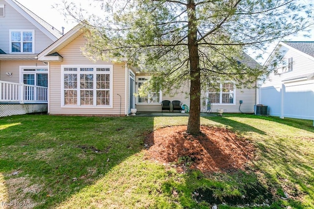 back of property featuring a lawn, central AC, and fence