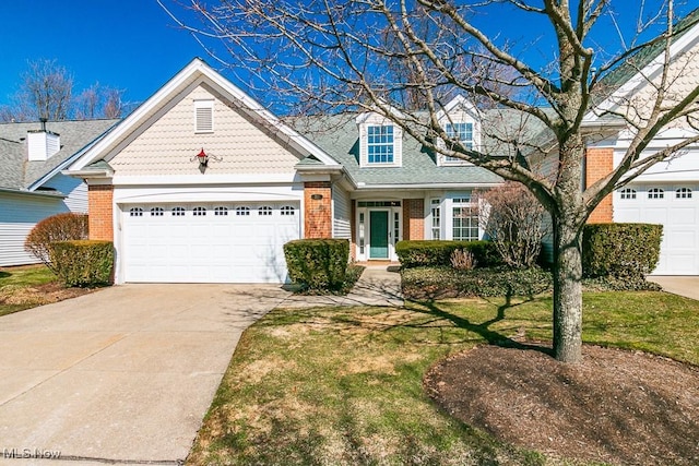 view of front of property featuring brick siding, driveway, a front yard, and a garage