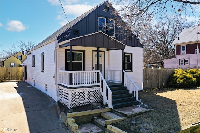 view of front of house featuring covered porch, board and batten siding, and fence