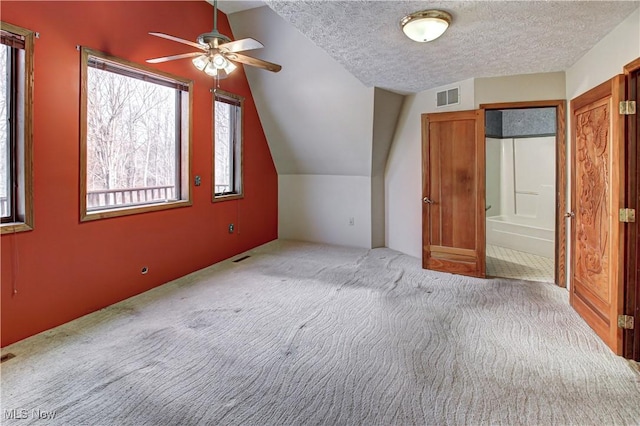 additional living space featuring visible vents, a ceiling fan, a textured ceiling, carpet floors, and lofted ceiling