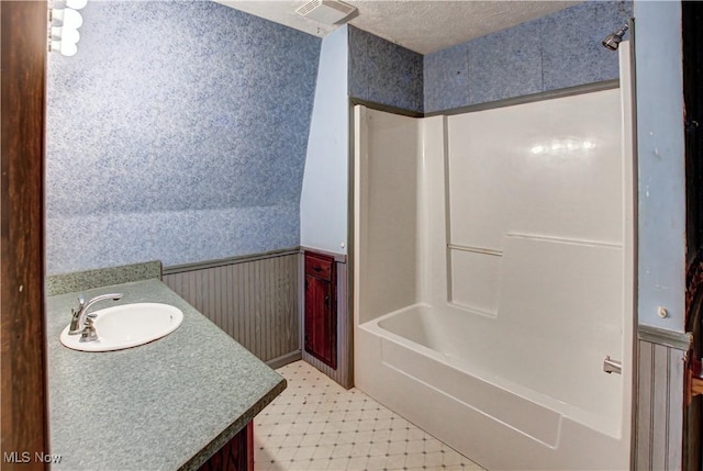 bathroom with visible vents, vanity, wainscoting, and wallpapered walls