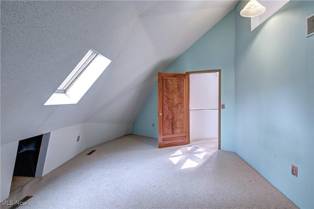 additional living space with visible vents, carpet floors, a textured ceiling, and vaulted ceiling with skylight